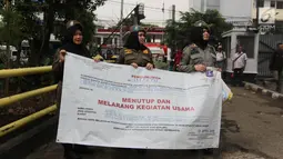 Petugas Satpol PP wanita membawa spanduk penutup saat akan menyegel Diskotek Exotic di Mangga Besar, Jakarta, Kamis (19/4). Segala kegiatan yang berada di dalam Diskotek Exotic pun dinyatakan terlarang alias ilegal. (Liputan6.com/Arya Manggala)