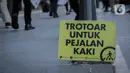 Poster bertuliskan Trotoar Untuk Pejalan Kaki terlihat di Trotoar Thamrin, Jakarta, Rabu (22/1/2020). Aksi tersebut dalam rangka memperingati Hari Pejalan Kaki Nasional pada 22  Januari, serta  mengajak pengendara untuk tertib lalu lintas serta menghormati hak pejalan kaki. (Liputan6.com/Faizal Fana