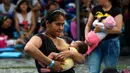 Seorang wanita menyusui bayinya saat mengikuti acara promosi manfaat menyusui, di sebuah taman di Bogota, Kolombia(3/11). Ratusan ibu menyusui bayi mereka untuk mempromosikan pemberian ASI sebagai bagian dari hak bayi. (AFP Photo/Raul Arboleda)