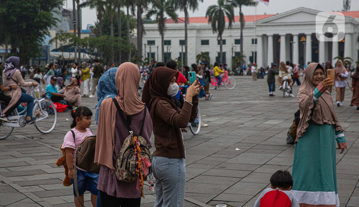 Wisatawan menikmati suasana Kota Tua, Jakarta, Selasa (26/12/2023). (Liputan6.com/Faizal Fanani)