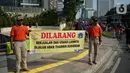 Petugas Satpol PP membentangkan spanduk larangan berjualan di jalur Hari Bebas Kendaraan Bermotor atau Car Free Day, Jakarta, Minggu (3/11/2019). Pemprov DKI melarang PKL berjualan di sepanjang jalur Car Free Day yang selama ini memenuhi badan jalan maupun trotoar. (Liputan6.com/Immanuel Antonius)
