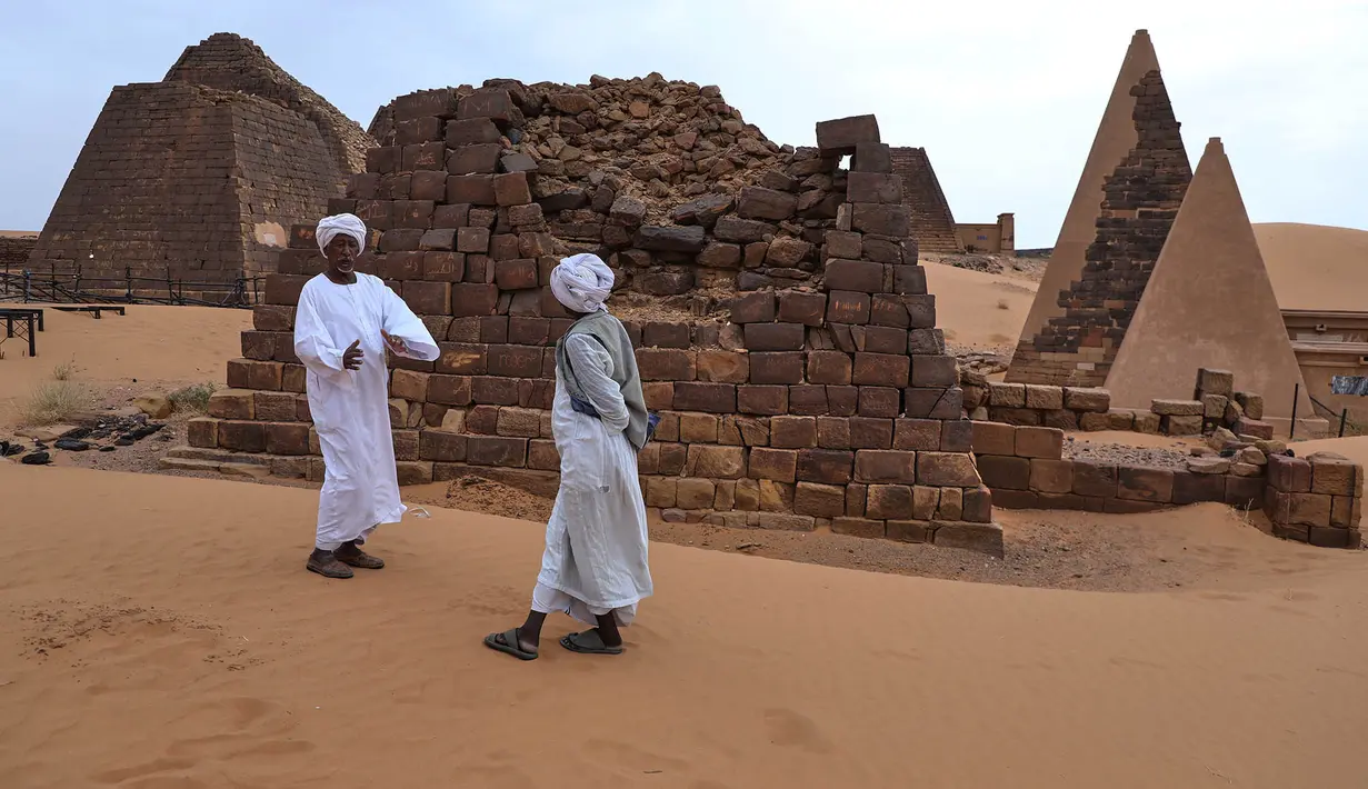 Seorang pemandu (kiri) berbicara dengan pengunjung di situs arkeologi Meroe di Bejrawiya, Sudan, Minggu, 2 Agustus 2026. (Foto AP/Mohnd Blal)