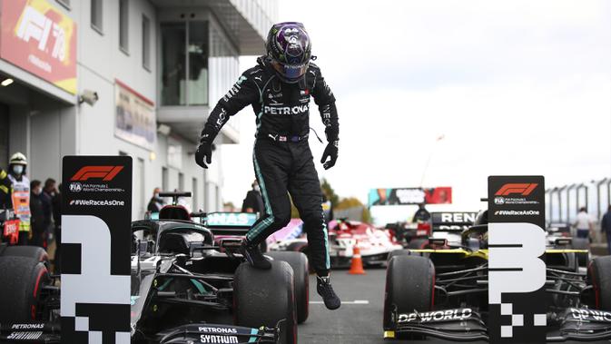 Pembalap Mercedes Lewis Hamilton melompat dari mobilnya setelah memenangkan F1 GP Eifel di Nuerburgring, Nuerburg, Jerman, Minggu (11/10/2020). Hamilton dengan 91 kemenangannya menyamai legenda F1 Michael Schumacher. (Bryn Lennon, Pool via AP)