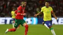 Gelandang Timnas Brasil, Casemiro (kanan) membayangi pergerakan gelandang Maroko, Hakim Ziyech pada laga persahabatan FIFA Matchday di Ibn Batouta Stadium, Tangier, Maroko (26/3/2023). Tampil sebagai kapten tim dan bermain penuh selama 90 menit, Casemiro gagal membawa Brasil terhindar dari kekalahan 1-2 meski ia mampu menyumbang satu-satunya gol untuk Timnas Brasil. (AFP/Fadel Senna)