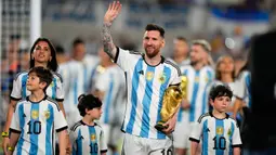 Lionel Messi berjalan ditemani Antonela Roccuzzo dan anak-anak mereka dengan membawa trofi Piala Dunia sambil menyapa para penonton. (AP Photo/Natacha Pisarenko)