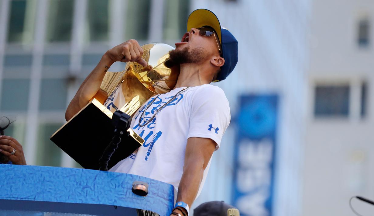 Pemain Guard Golden State Warriors, Stephen Curry memeluk tropi Larry O'Brien saat menggelar parade Warriors 2018 usai menjuarai NBA 2018 di pusat kota Oakland, California, Amerika Serikat, (12/6). (AP Photo/Marcio Jose Sanchez)