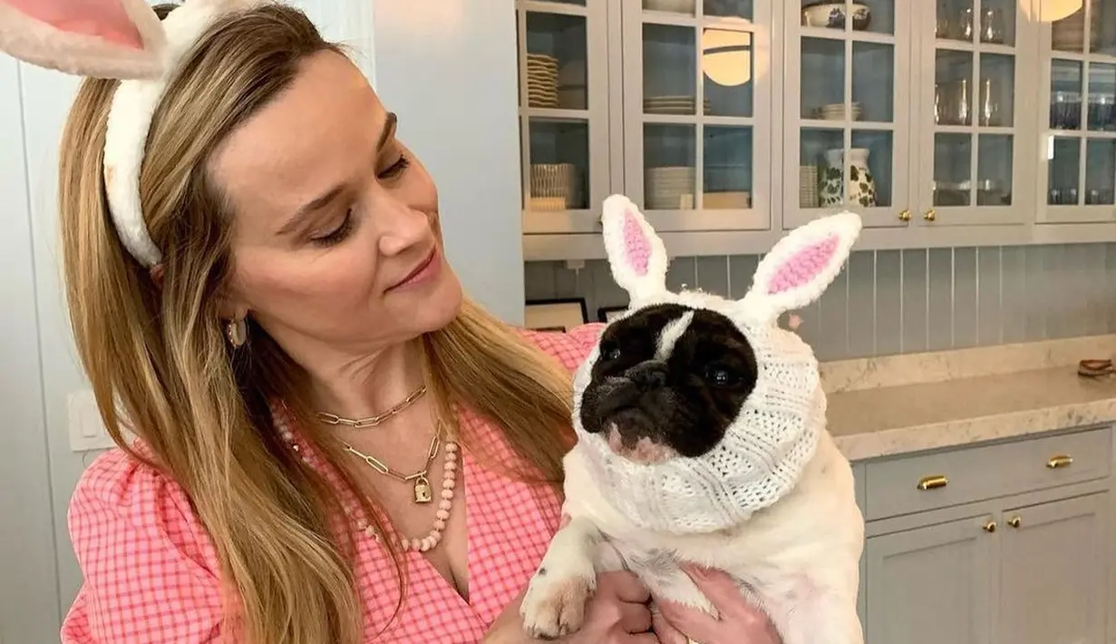 Reese Whiterspoon tampil manis di Paskah kali ini. Ia mengenakan dress lengan pendek kotak-kotak merah muda, mengenakan bando telinga kelinci yang juga bernuansa merah muda, menggendong anjing peliharaannya yang diberi kostum telinga kelinci yang menggemaskan. Foto: Instagram.