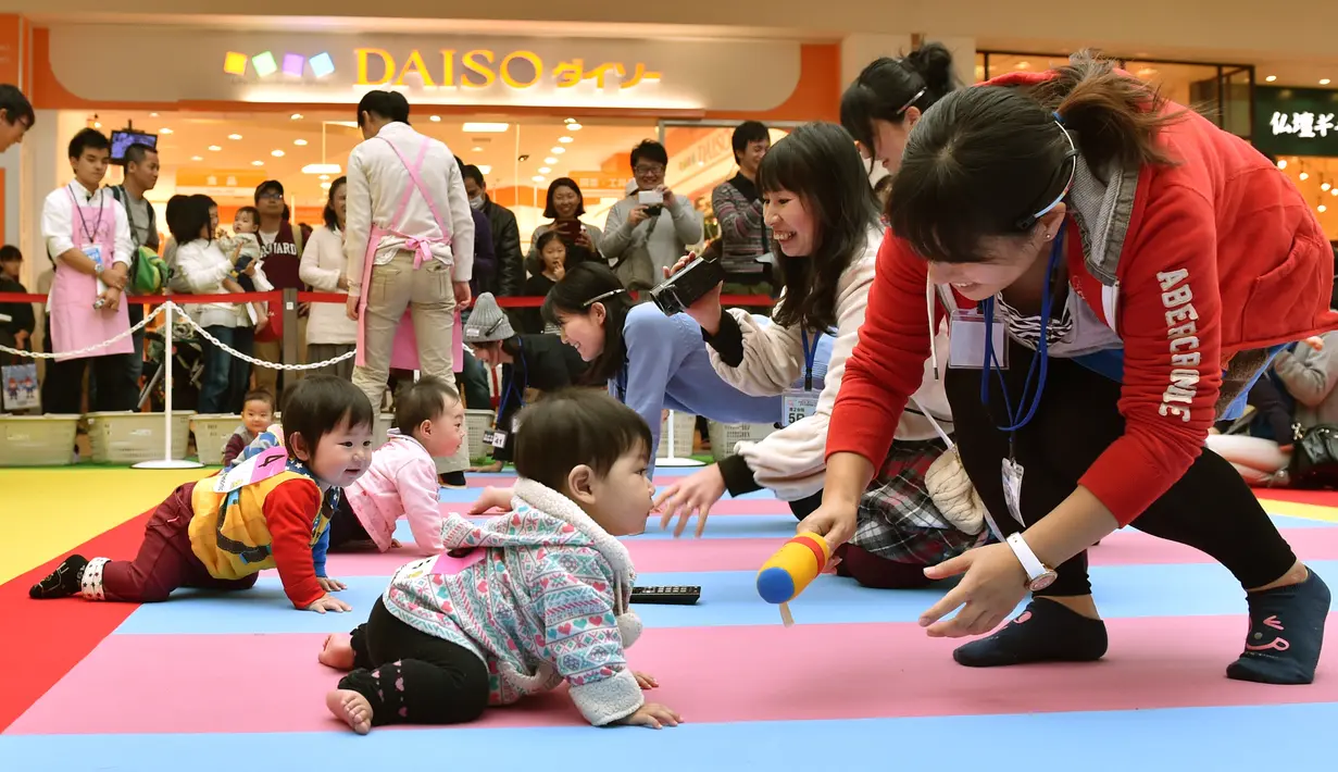 Sejumlah ibu menarik perhatian anaknya untuk mencapai garis finis saat mengikuti kompetisi 'Bayi Merangkak',  Yokohama, Jepang, Senin (23/11/2015). Tingkah bayi yang lucu menjadi pemandangan yang menggemaskan bagi para penonton. (AFP Photo/Kazuhiro Nogi)