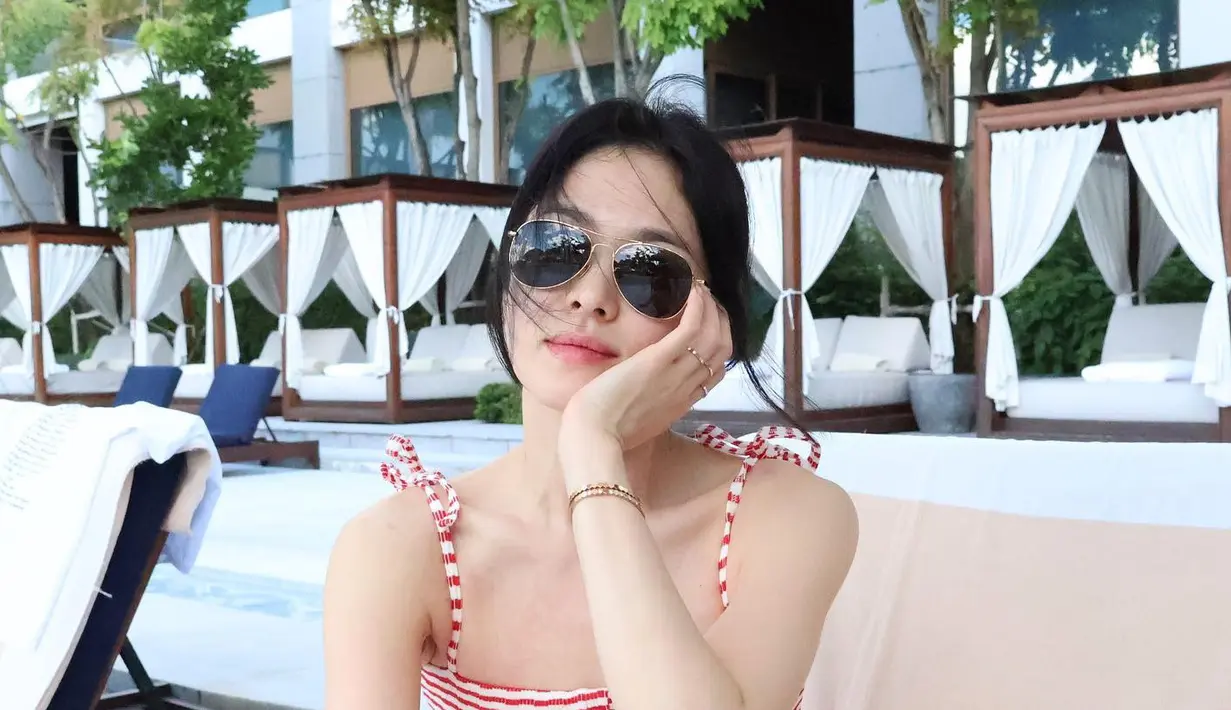 <p>Detail pita pada tali bahunya mempercantik kesan femininnya, sementara memadukannya dengan topi bisbol dan kacamata hitam bundar menciptakan tampilan yang stylish. (Foto: Instagram/ kyo1122)</p>