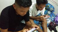 Dua pemain Persis Solo, Tegar Hening Pangestu (kiri) dan Dedi Tri Maulana saat asyik bermain PUBG Mobile di mes Persis Solo, Kamis (4/4/2019). (Bola.com/Vincentius Atmaja)