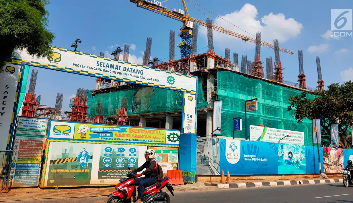 Pengendara motor melintas di depan pembangunan rumah susun terintegrasi dengan sarana transportasi di samping Stasiun KA Tanjung Barat, Jakarta Selatan, Kamis (11/7.2019). Pembangunan hunian TOD Tanjung Barat merupakan hasil kerja sama PT KAI dan Perum Perumnas. (Liputan 6.com/Immanuel Antonius)