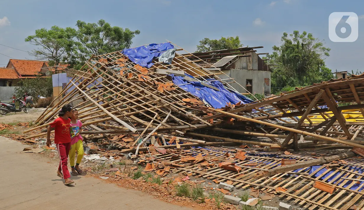 Anak-anak melintasi puing-puing bangunan rumah yang rusak diterjang angin puting beliung di Kaliabang Tengah, Kota Bekasi, Sabtu (24/10/2020). Menurut Badan Penanggulangan Bencana Daerah (BPBD) sebanyak 159 rumah terdampak puting beliung yang terjadi Jumat siang. (Liputan6.com/Herman Zakharia)