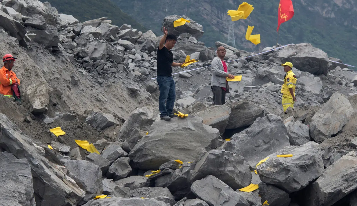 Keluarga korban melemparkan kertas ritual untuk menenangkan arwah orang yang tewas di lokasi tanah longsor di desa Xinmo, Sichuan, China (25/6). Sekitar 118 orang hilang diduga tertimbun bebatuan akibat longsor ditempat tersebut. (AP Photo / Ng Han Guan)