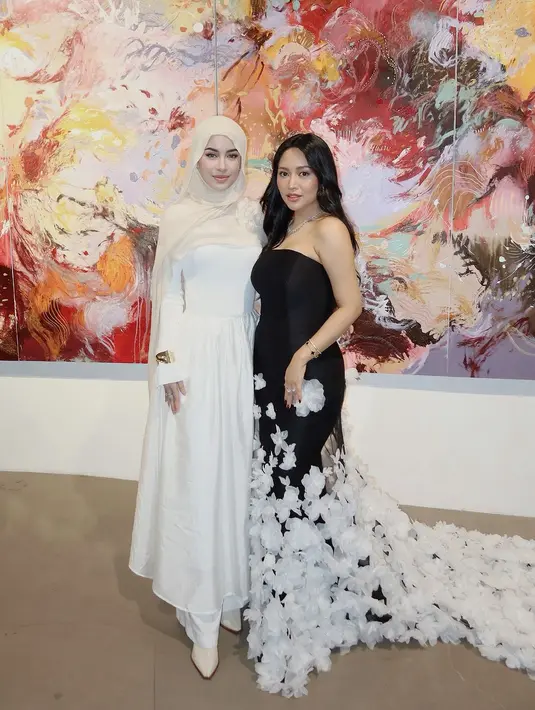 Kemudian Emy Aghnia yang tampil dengan maxi dress putih dan pashmina warna beige. Aksesori gelang emas di tangan menambah impresi elegan pada penampilan simple-nya. [@emyaghnia].