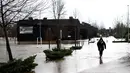Seorang wanita melalui genangan air di Coimbra, Portugal (14/2/2016). Banjir yang terjadi di Coimbra diakibatkan oleh meluapnya sungai Mondego setelah diguyur hujan selama 24 jam. (AFP Photo /Francisco Leong)