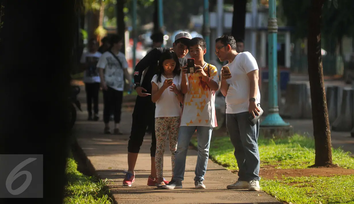Sejumlah pemuda dan anak- anak saat berburu pokemon di Kawasan Senayan, Jumat (15/7).Permainan Pokemon Go ini menugaskan para pemainnya untuk memburu pokemon mereka sendiri. (Liputan6.com/Gempur M Surya)
