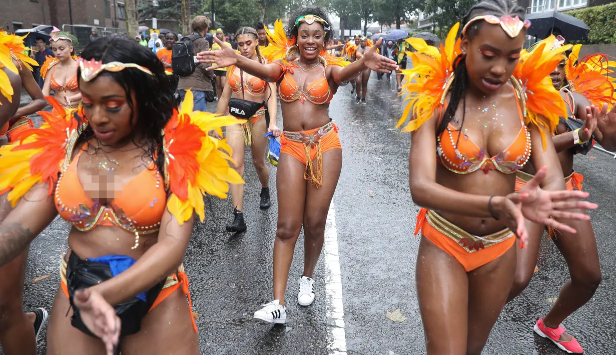 Penari karnaval menari di tengah hujan selama parade hari pertama Karnaval Notting Hill di London barat, Minggu (26/8). Karnaval Notting Hill yang merupakan pawai jalanan terbesar di Eropa diadakan setiap tahun sejak tahun 1966. (AFP/Daniel LEAL-OLIVAS)