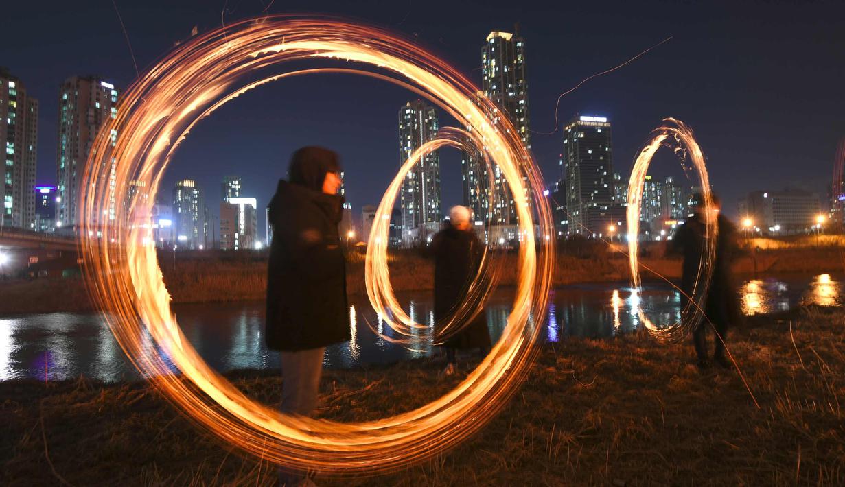 Peserta memutar kaleng arang yang terbakar menjelang perayaan "Jeongwol Daeboreum" (Bulan Purnama) di sebuah taman di Seoul, Korea Selatan (1/3). Permainan ini dipercaya dapat menyuburkan tanah dan menyingkirkannya hama. (AFP Photo/Jung Yeon-je)