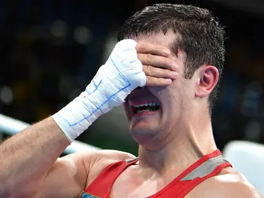 Atlet tinju Uzbekistan, Rustam Tulaganov menangis sambil menutupi wajahnya dengan tangan usai menang atas petinju Azerbaijan, Abdulkadir Abdullayev dalam pertandingan tinju putra kelas 91 kg di Olimpiade Rio 2016, 10 Agustus 2016. (AFP PHOTO/Yuri CORTEZ)