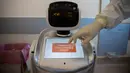 Wakil kepala unit perawatan intensif Flavio Tangian, menggunakan layar sentuh robot di rumah sakit 'Ospedale di Circolo', di Varese, Italia, 8 April 2020. Sebanyak enam unit robot yang berjalan di atas roda ini membantu kinerja staf medis dalam merawat pasien virus corona Covid-19. (AP/Luca Bruno)