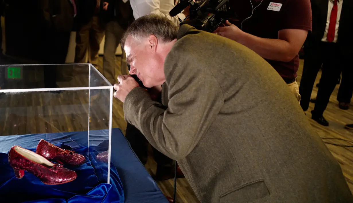 Rhys Thomas, penulis "the Ruby Slippers of Oz" mengambil foto sepasang sepatu ruby yang pernah dikenakan aktris Judy Garland dalam "The Wizard of Oz" saat konferensi pers di Kantor FBI, Minnesota, Selasa (4/9). (Richard Tsong-Taatarii/Star Tribune via AP)