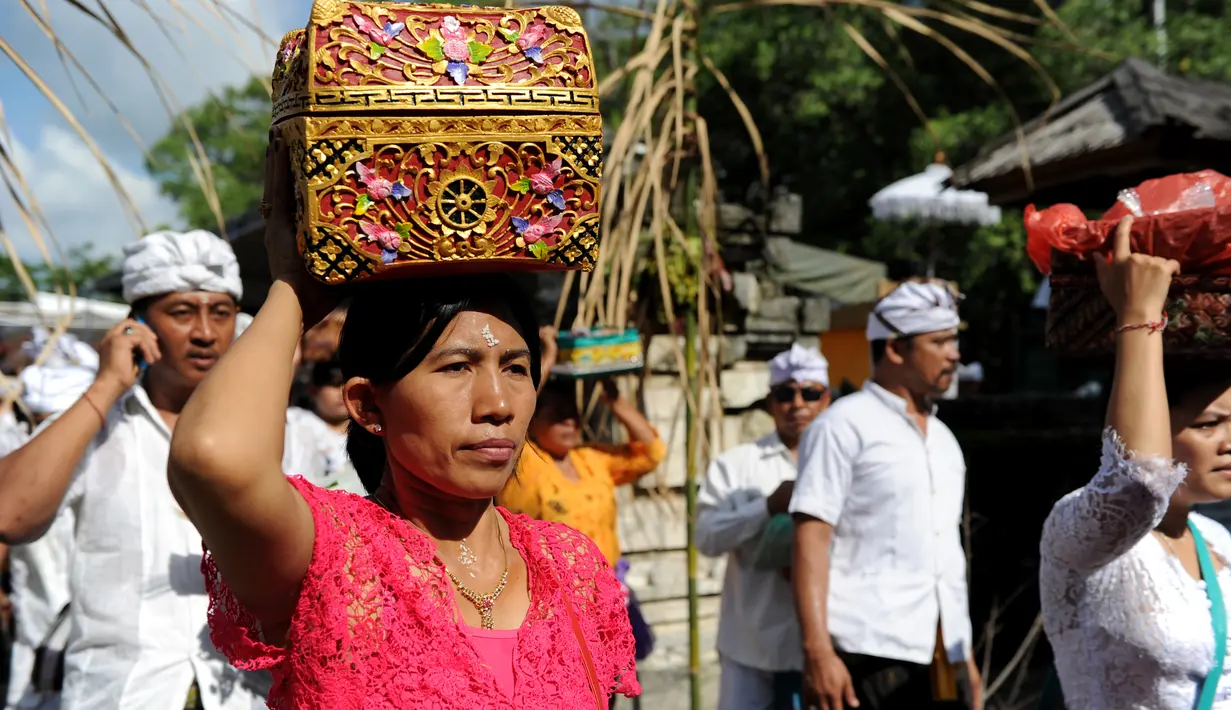Umat Hindu membawa sesajen sebelum berdoa saat perayaan Kuningan di sebuah pura di Pulau Serangan, Denpasar, Bali, Sabtu (20/2). Kuningan merupakan hari terakhir dari perayaan Galungan. (AFP PHOTO/SONNY Tumbelaka)