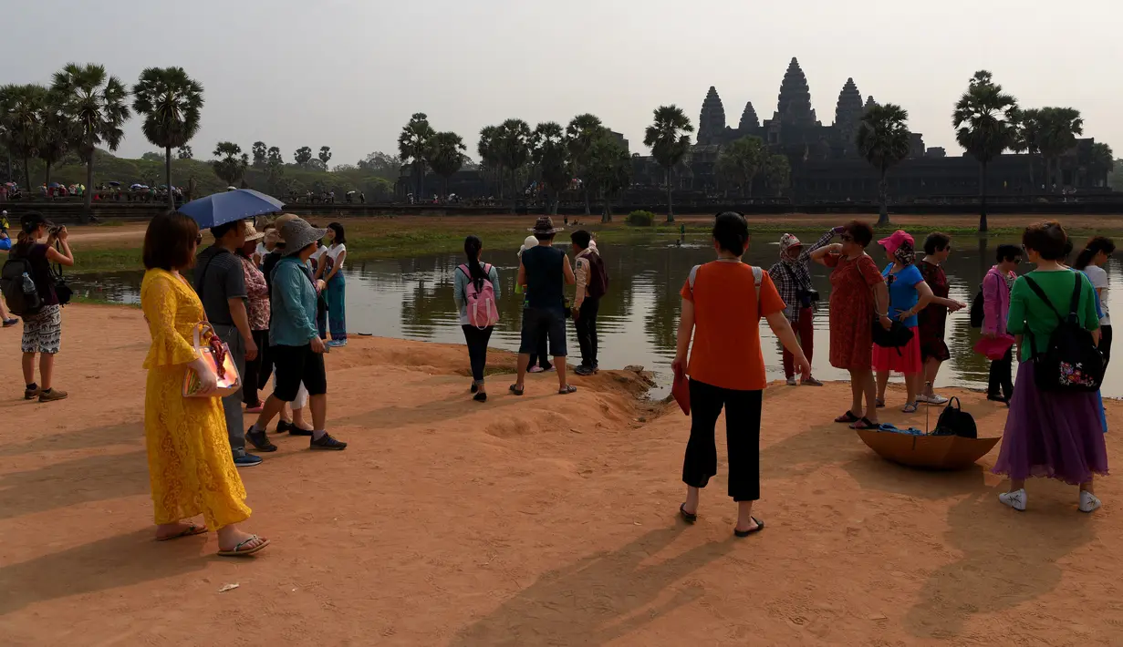 Turis mengunjungi candi Angkor Wat di provinsi Siem Reap, barat laut Kamboja pada 16 Maret 2019. Angkor Wat terkenal memiliki lebih dari 3000 Apsaras, relief berwujud perempuan, yang dipahat di setiap dindingnya. (TANG CHHIN Sothy / AFP)