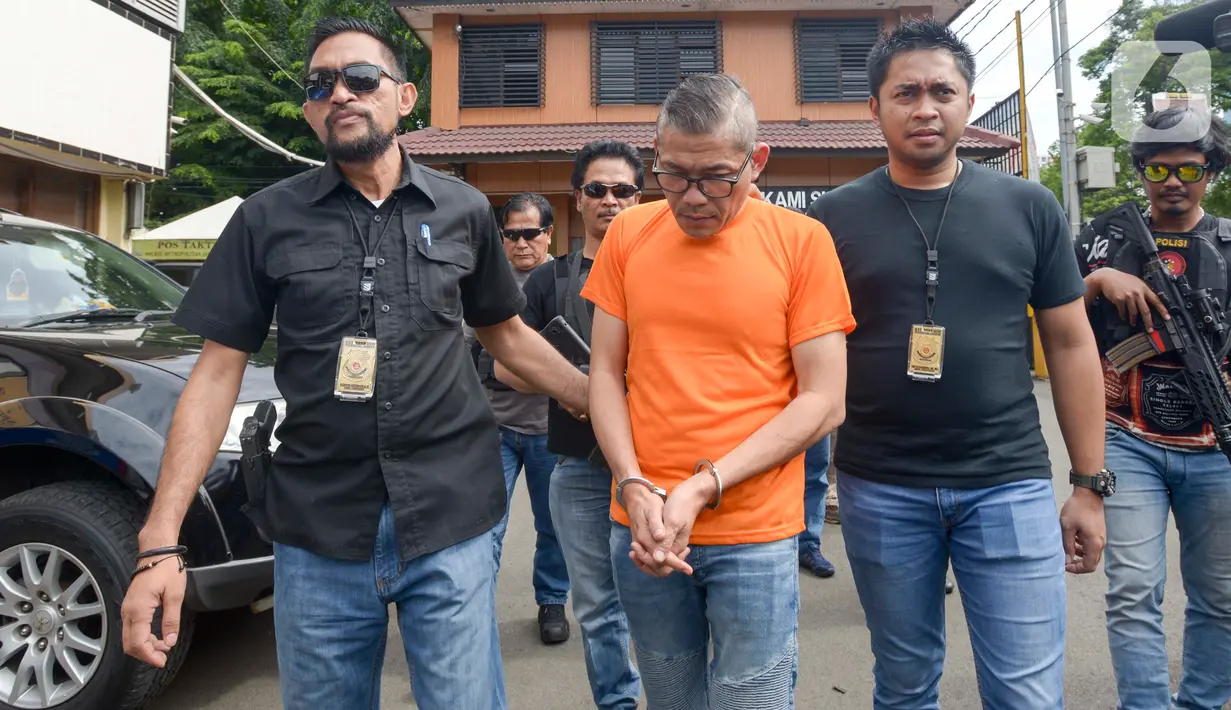 Pengemudi yang mendorong-dorong dan mencekik polisi saat hendak ditilang dekat Gerbang Tol Angke tertunduk saat diamankan Polres Jakarta Barat, Sabtu (8/2/2020). Polisi menangkap pria berinisial TS tersebut setelah videonya mengajak duel polisi sempat viral di media sosial. (merdeka.com/Imam Buhori)