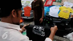 Warga melihat kaos berlogo Muktamar ke-33 Nahdlatul Ulama yang dijual di Jombang, Jawa Timur, Senin (3/8/2015). Pernak-pernik yang dijual yakni kaos, pin, gantungan kunci, dan berbagai produk kerajinan tangan lainnya. (Liputan6.com/Johan Tallo) 