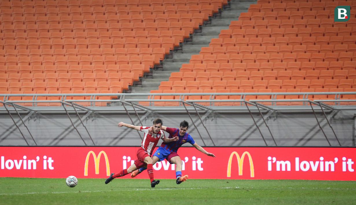 Pemain Barelona U-18, Marc Guiu Paz (kanan) berebut bola dengan pemain Atletico Madrid U-18, Hugo Martin Gonzalez saat laga International Youth Championship 2021 di Jakarta International Stadium, Jakarta, Jumat (15/04/2022). (Bola.com/Bagaskara Lazuardi)