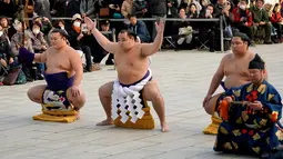 Juara Grand Sumo asal Mongolia, Kakuryu (kedua kiri) melakukan upacara mengentakkan kaki di Kuil Shinto Meiji Shrine, Tokyo, Selasa (9/1). Merujuk kepada Wikipedia, ritual tersebut dikenal dengan nama shiko. (AP/Shizuo Kambayashi)