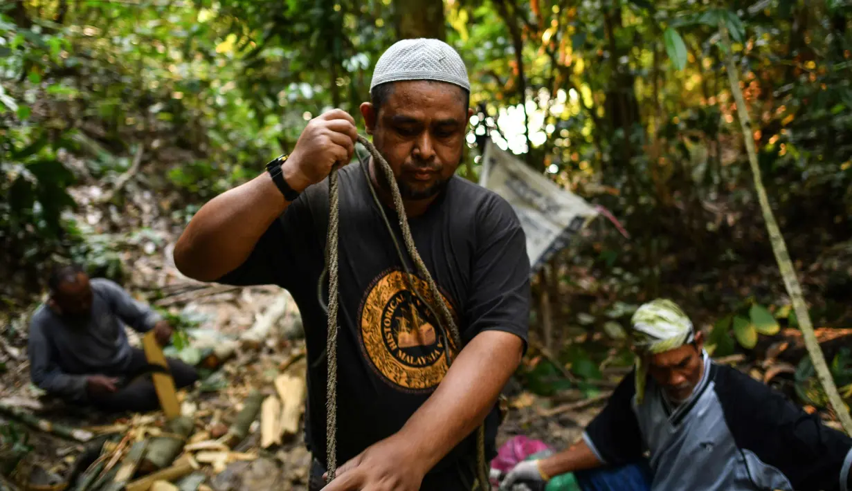 Pemburu madu tradisional Malaysia menyiapkan tali dan papan kayu yang dibutuhkan untuk memperbaiki tangga untuk memanen madu di atas pohon Tualang raksasa di hutan Ulu Muda di Sik, Malaysia, Kedah (11/3). (AFP Photo/Manan Vatsyayana)