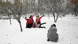 Sejumlah wanita berpose saat salju turun di sebuah taman di Beijing (16/12/2019). Pada pukul 7 Senin pagi, 42 penerbangan telah dibatalkan di Bandara Internasional Ibukota Beijing. (AFP Photo/Wang Zhao)