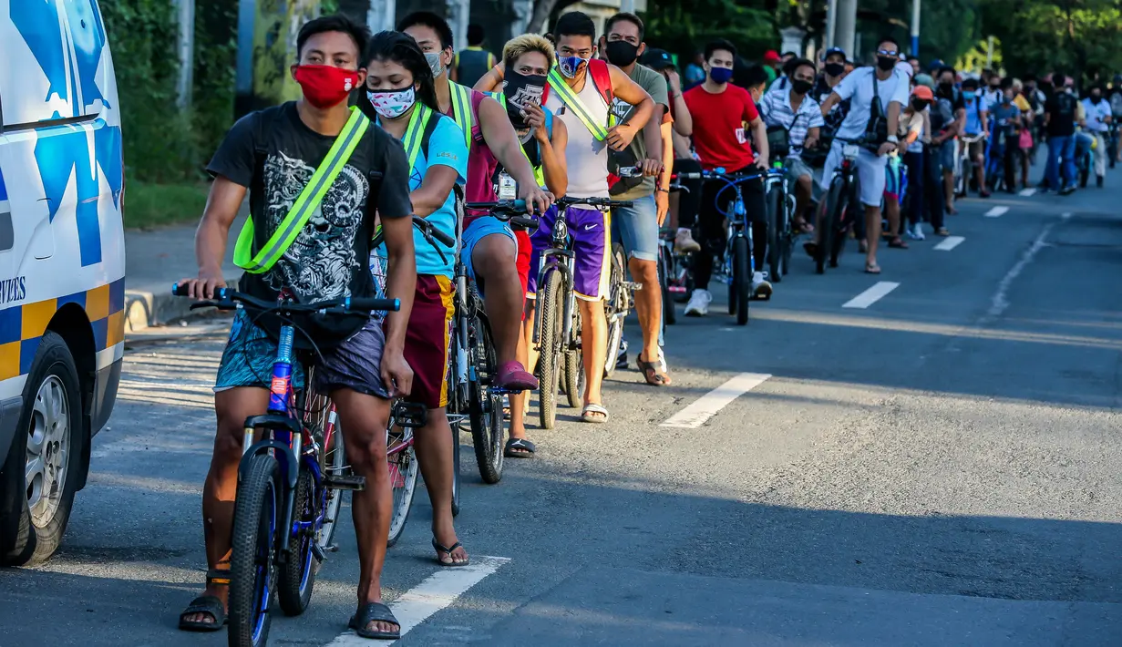 Para pengendara sepeda mengantre untuk mendapatkan helm dan selempang reflektif gratis yang dibagikan oleh sejumlah anggota lembaga swadaya masyarakat di Manila, Filipina (9/7/2020). (Xinhua/Rouelle Umali)