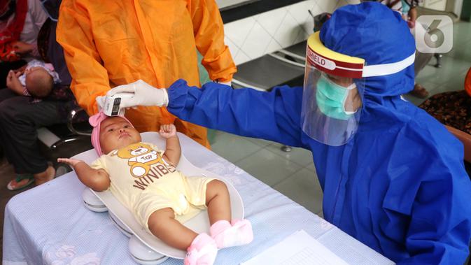 Bidan mengenakan alat pelindung diri (APD) saat melakukan imunisasi kepada bayi di Puskesmas Karawaci Baru, Tangerang, Banten, Rabu (13/5/2020). Pelayanan imunisai sesuai jadwal ini diberikan kepada bayi untuk menambah kekebalan imun tubuh. (Liputan6.com/Angga Yuniar)