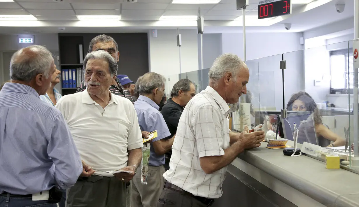 Tampak seorang melakukan transaksi di Bank Piraeus di kota Iraklio, Yunani (20/7/2015). Negosiasi formal untuk dana talangan baru rencananya akan bernilai sebesar 86 miliar euro. (REUTERS / Ronen Zvulun)