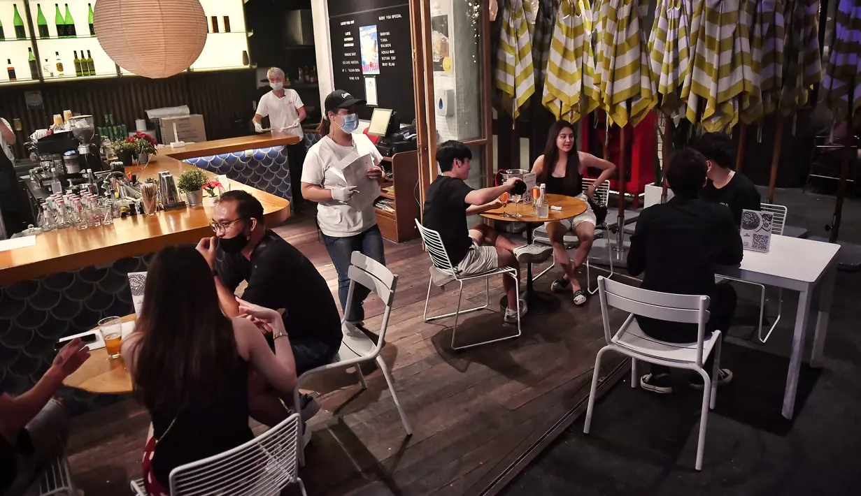 Pelayan melayani pelanggan di sebuah bar di Bangkok, Thailand, Rabu (1/7/2020). Mulai 1 Juli, bar di Bangkok kembali diizinkan buka setelah pengurangan pembatasan akibat COVID-19. (Lillian SUWANRUMPHA/AFP)