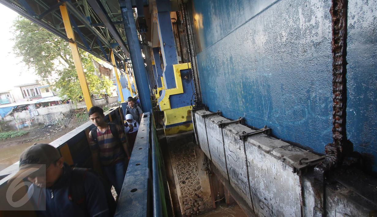 Tidak tersedianya jembatan penyeberangan orang menyebabkan warga harus melintasi jalan setapak di pintu air Petamburan untuk menyeberangi aliran Kanal Banjir Barat (KBB), Jakarta, Jumat (17/2). (Liputan6.com/Immanuel Antonius)