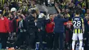 Pelatih Besiktas, Senol Gunes memegangi kepalanya setelah terkena lemparan benda tajam dari tribun penonton pada semifinal Piala Turki melawan Fenerbahce di Istanbul, Kamis (19/4). Gunes harus dilarikan ke rumah sakit dan menerima lima jahitan. (AFP)