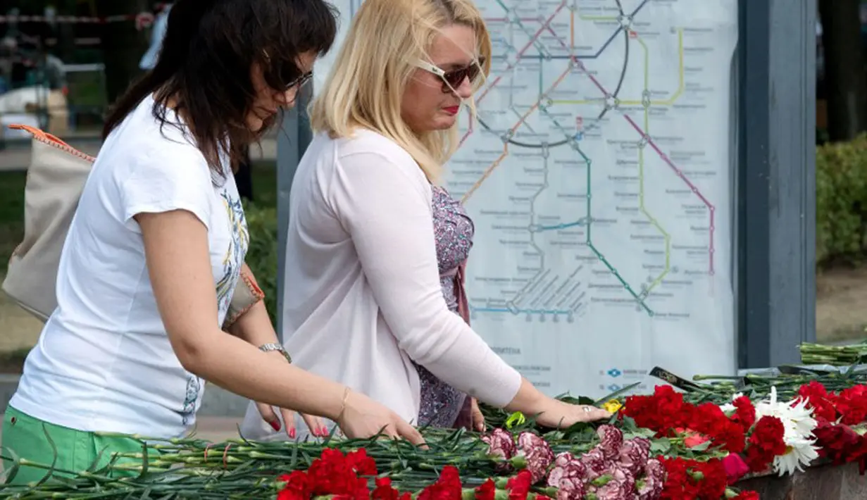 Beberapa wanita meletakkan karangan bunga di pintu masuk Stasiun Park Pobedy, lokasi tergelincirnya kereta bawah tanah, Moskow, (16/7/2014). (AFP PHOTO/Dmitry Serebryakov)