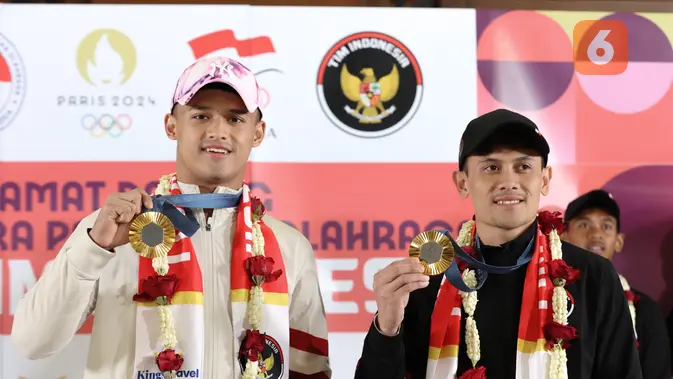 <p>Dua atlet Indonesia peraih medali emas di Olimpiade 2024 Paris Rizki Juniansyah (kiri) dan Veddriq Leonardo (kanan) memamerkan medalinya usai tiba di Bandara Internasional Soekarno-Hatta, Tangerang, Selasa (13/8/2024). (Abdul Aziz/Bola.com).</p>