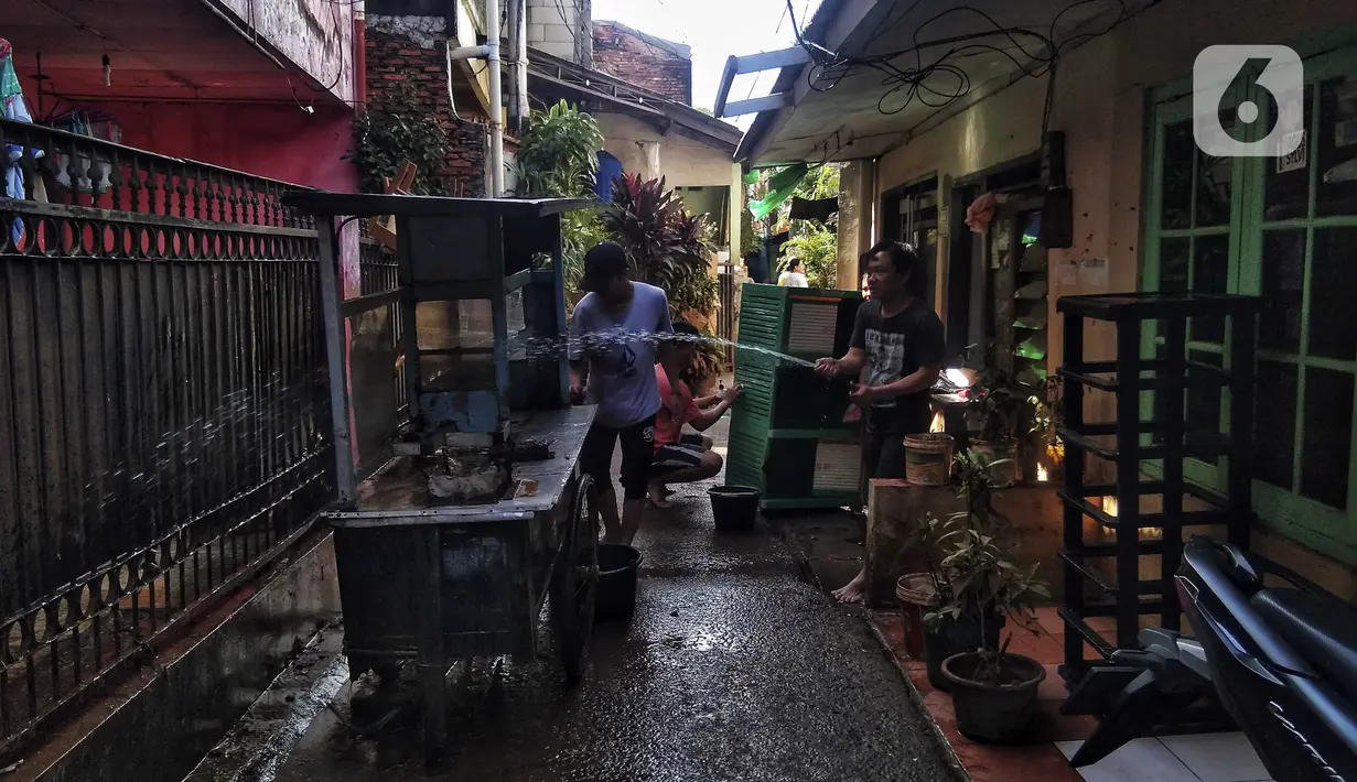 Warga membersihkan gerobak usai banjir di Kebalen, Jakarta, Minggu (21/2/2021). Banjir yang terjadi kemarin karena curah hujan yang tinggi meninggalkan sampah di rumah warga. (Liputan6.com/Johan Tallo)