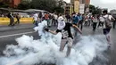 Demonstran melempar gas air mata yang telah ditembakkan polisi saat aksi menentang Presiden Venezuela Nicolas Maduro di Caracas, kamis (20/4). Tiga orang dikabarkan tewas dalam aksi demonstrasi tersebut.  (AFP PHOTO/ Juan BARRETO)