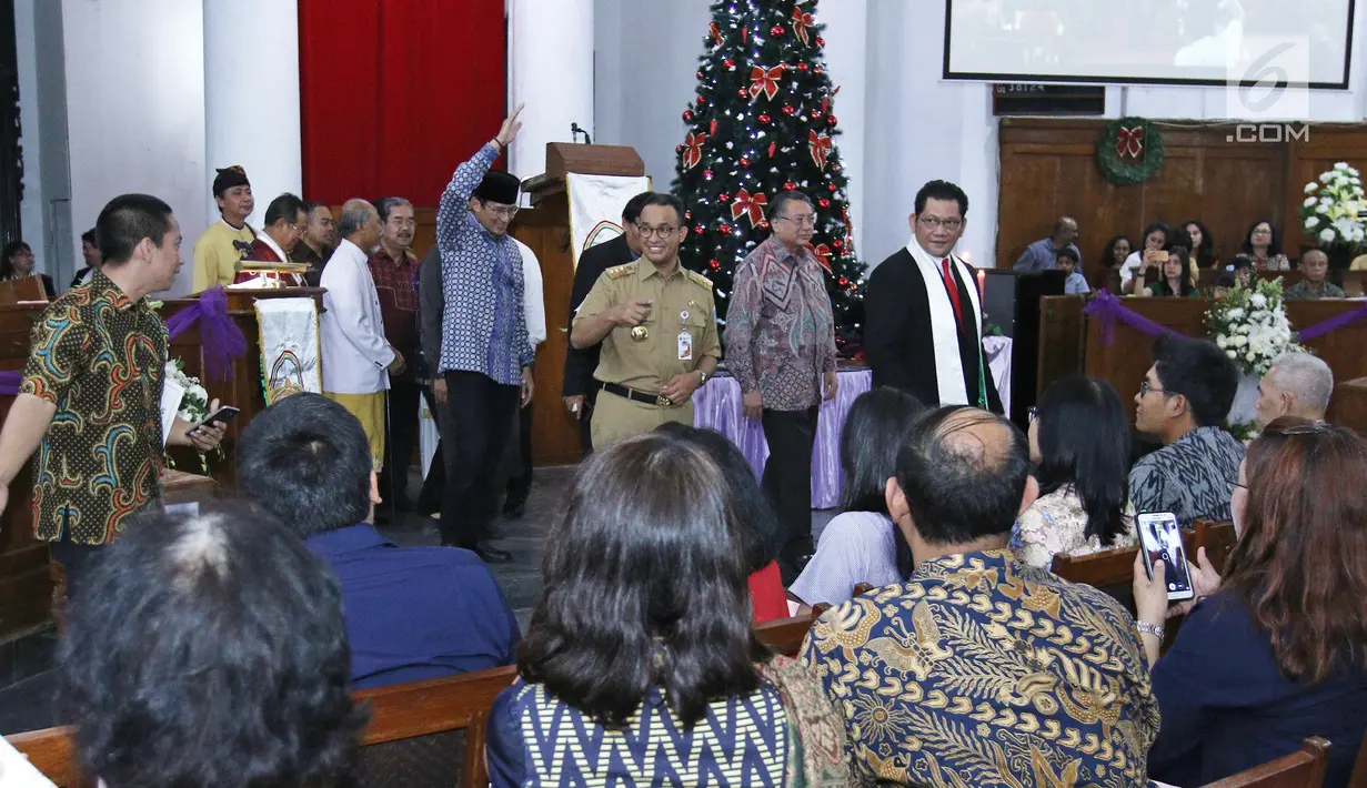 Gubernur DKI Jakarta Anies Baswedan dan Wagub Sandiaga Uno menyapa jemaat usai memberikan sambutan pada malam Misa Natal di Gereja Protestan Indonesia Barat (GPIB) Immanuel, Gambir, Jakarta, Minggu (24/12). (Liputan6.com/Herman Zakharia)