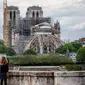 Seorang wanita mengamati Katedral Notre-Dame yang tengah dipugar di Paris, Prancis, Senin (27/4/2020). Renovasi Katedral Notre-Dame dilanjutkan kembali setelah sempat dihentikan sejak 17 Maret lalu akibat epidemi COVID-19. (Xinhua/Aurelien Morissard)