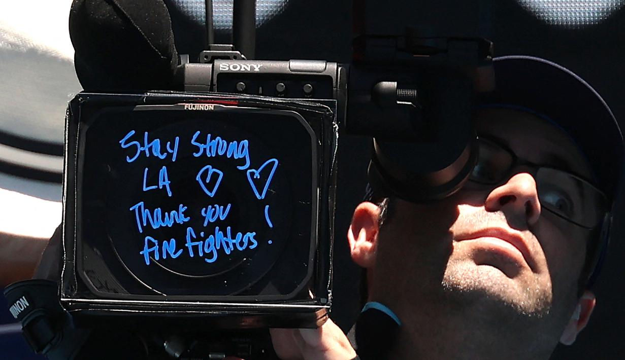 Pesan bertuliskan "tetap kuat Los Angeles dan terima kasih pemadam kebakaran" dari petenis Amerika Serikat, Coco Gauff setelah kemenangannya atas kompatriotnya, Sofia Kenin pada hari kedua Australia Open 2025 di Melbourne, Australia, Senin (13/01/2025). (AFP/David Gray)