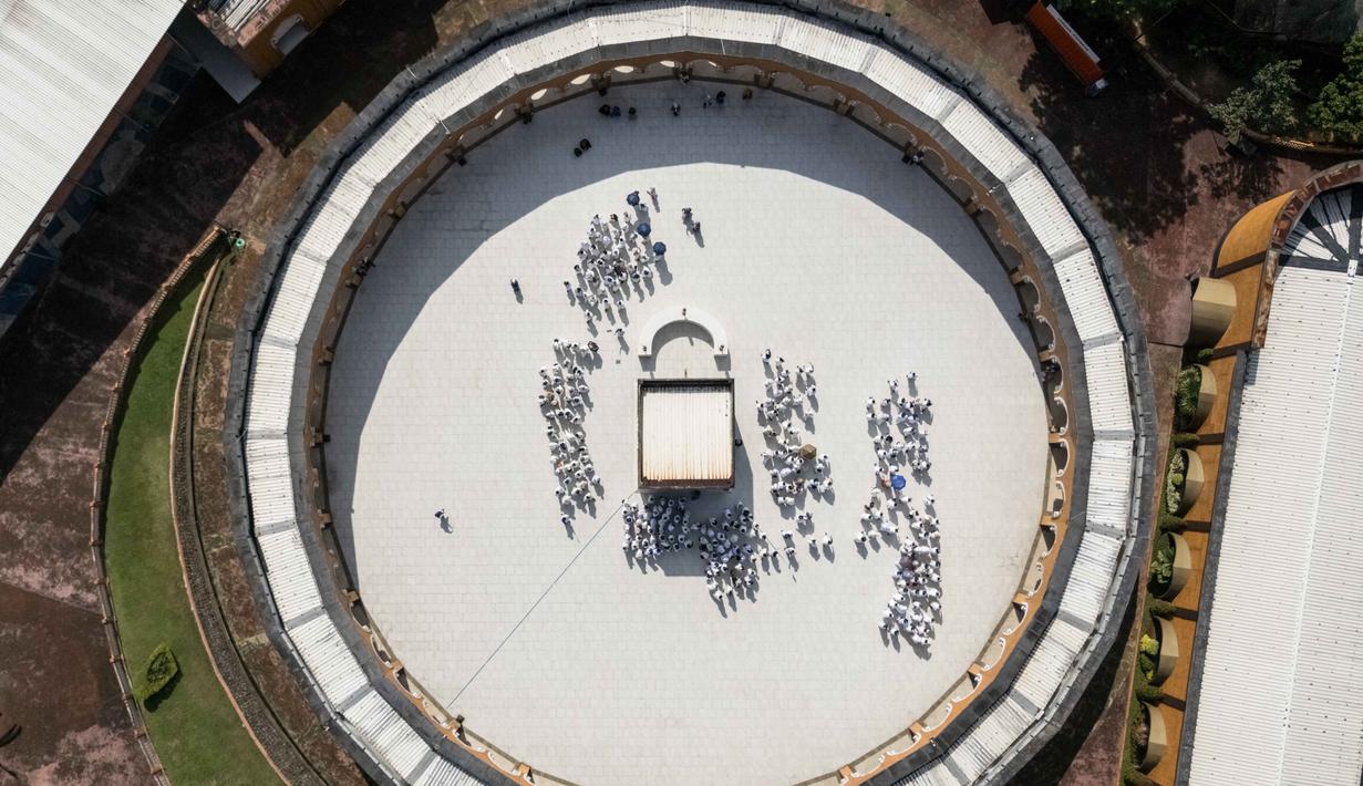 Sebuah gambar udara menunjukkan calon jemaah haji Indonesia berlatih ritual tawaf mengelilingi replika Ka'bah, selama sesi pelatihan di Pusat Pelatihan Manasik Al Mahmudah (AMTC) di Tangerang Selatan pada 5 April 2026. Presiden Prabowo Subianto memutuskan untuk menurunkan biaya haji 2026 sebesar Rp 2 juta. (Foto oleh AFP)