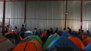 Imigran mengantre makanan di dalam tempat penampungan di Tijuana, Meksiko 6 April 2019. Rombongan migran Amerika Tengah mencapai kota perbatasan antara Meksiko dan AS tersebut  untuk mencari suaka akibat kekerasan, pembunuhan dan kemiskinan yang mengancam