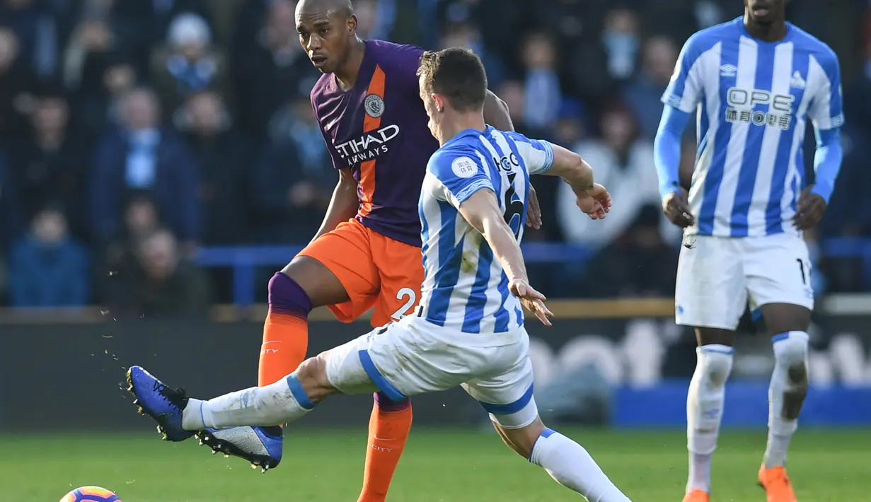 Gelandang Man City, Fernandinho saat dihadang pemain Huddersfield  pada laga lanjutan Premier League yang berlangsung di stadion John Smith, Huddersfield, Minggu (20/1). Manchester City menang 3-0 atas Huddersfield. (AFP/Paul Ellis)