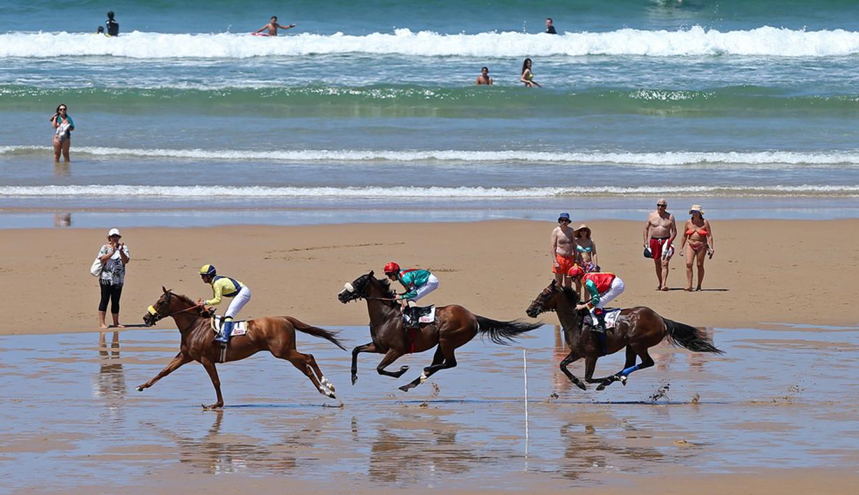 Para joki beraksi dalam kejuaraan tahunan pacuan kuda pantai di Loredo, Santander, Spanyol, (24/7/2016). (AFP/Cesar Manso)